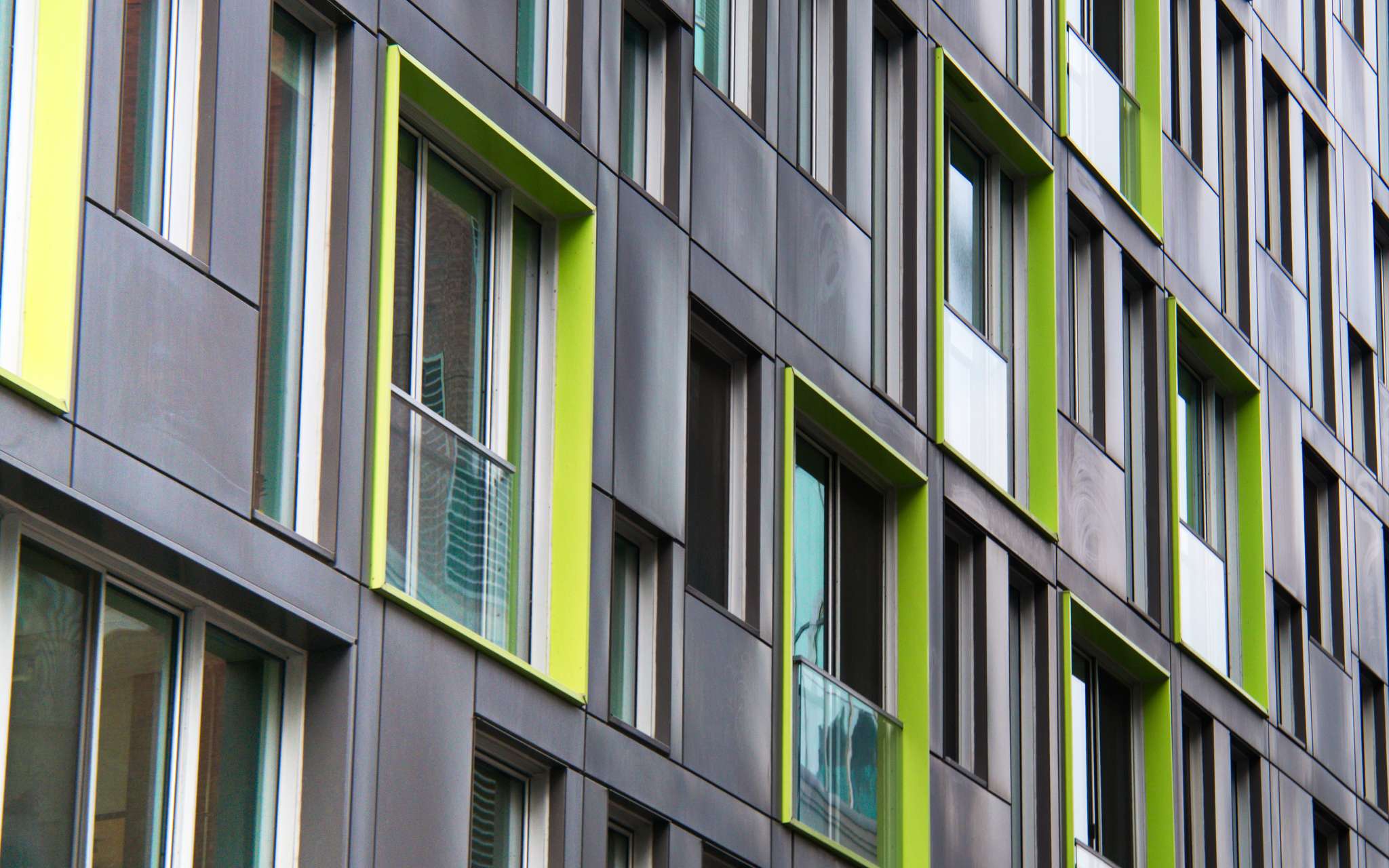 A grey facade with chartreuse window frames.